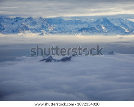 Amazing aerial view of misty swiss alps and clouds above the mountain peaks from airplane switzerland