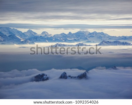 Amazing aerial view of misty swiss alps and clouds above the mountain peaks from airplane switzerland