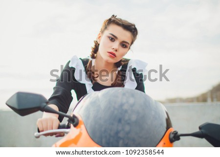 Standing schoolgirl with typical navy white uniform apron sits on motorcycle