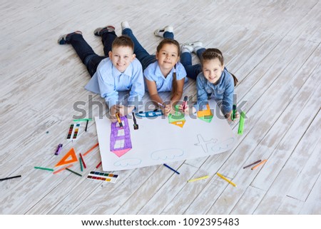 Three children drawing together on the floor