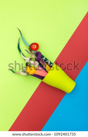 Pencils in a cover of fulled wool in a green cup on a colored background