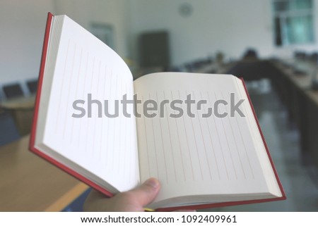 A close up of a hand holding a book in a meeting room selective focus and shallow depth of field