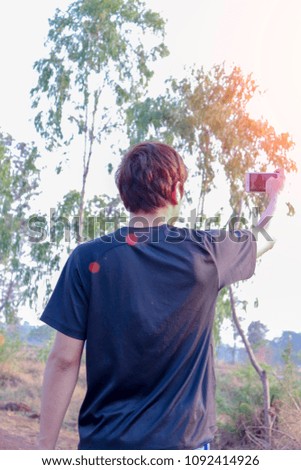 Tourism concept. Young man taking photo on smartphone while traveling Thailand With a sky background