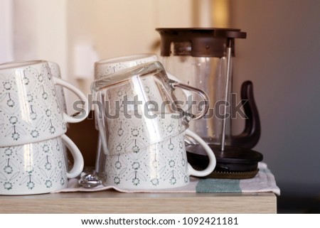 Clean tea cups and teapot on the tablecloth on wooden table with sunlight, toned, close-up. Party, tableware concept. Copy space