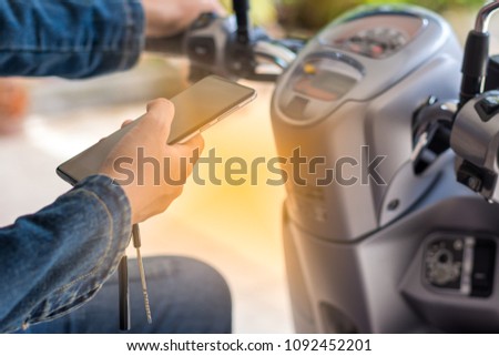 Young woman  sitting on motorcycle , hand holding mobile smart phone. Leisure time and travel concept.