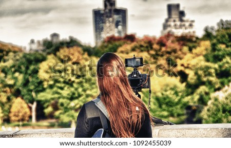 Female photographer taking shots of New York Central Park in autumn, foliage season.