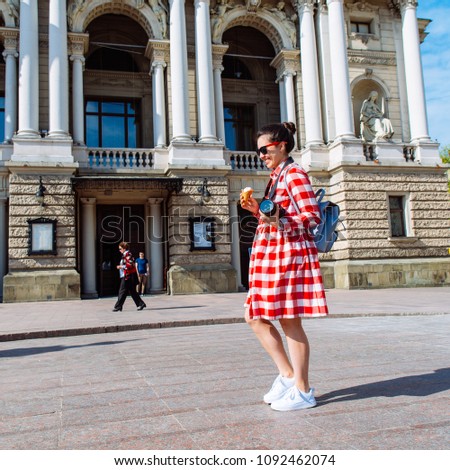 woman walk by center of european city with ice cream and camera. sunny day