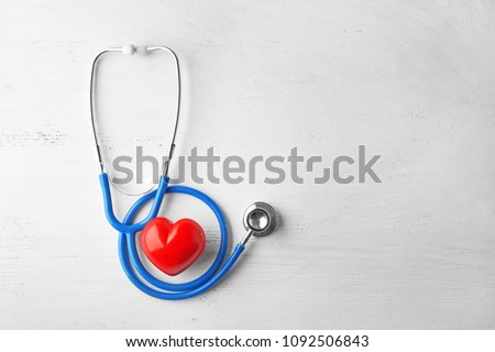 Stethoscope and red heart on white wooden background. Health care concept