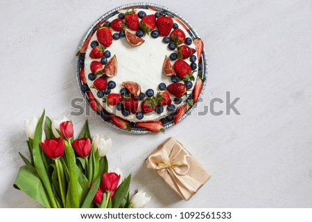 Cake with cream and mushroom and blueberries. Birthday gifts. Bouquet of flowers and cake