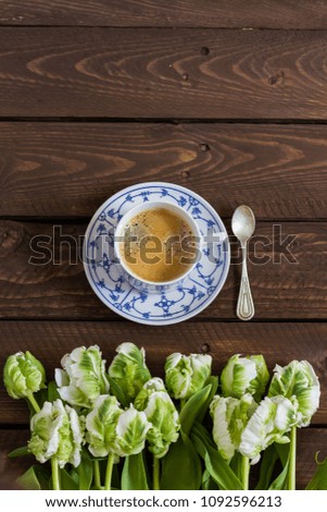 Coffee with flowers on the dark wooden table. Coffee in old porcelain cup. Flatlay.