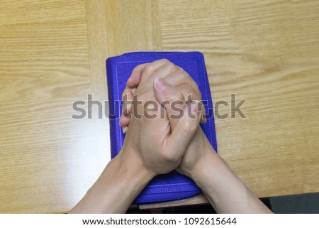 Two hands above biblical book Prayer