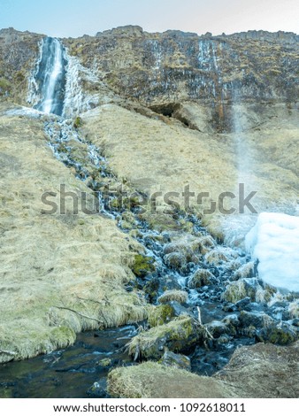 Large waterfall near Seljalandsfoss waterfall with large snow with small ascending fountain, in winter season in Iceland