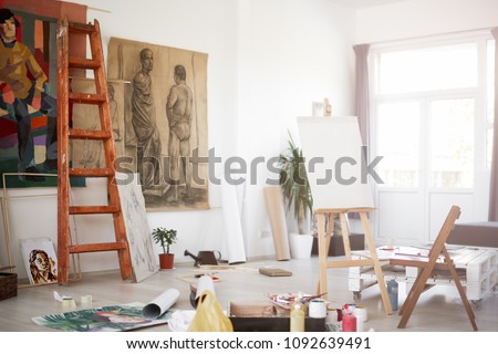Interior of artist`s atelier. Paintings and painting material all around. Royalty-Free Stock Photo #1092639491