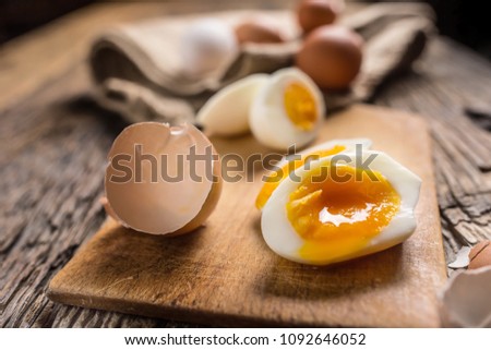 Close-up boiled or raw chicken eggs on wooden board.
