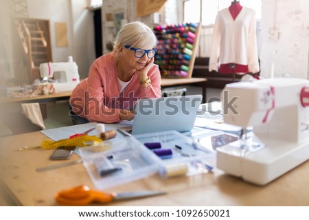 Confident senior fashion designer in her workshop 