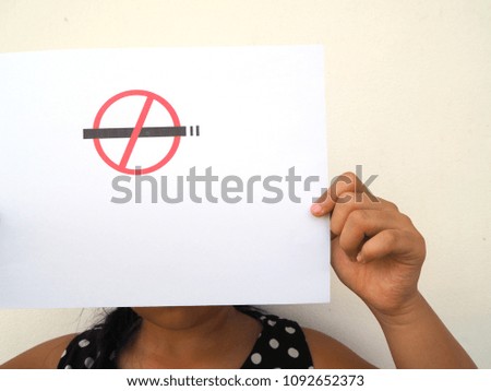 Little girl showing NO SMOKING sign on paper   