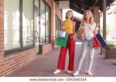 Beautiful women with credit cards shopping together in strip mall