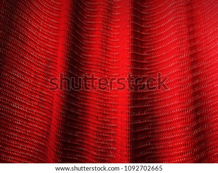 Red backgroundred mesh fabric texture. Macro perspective, red sailcloth fabric