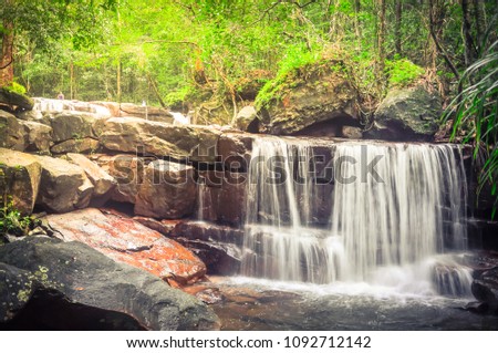 Vintage tone beautiful Suoi Tranh waterfall in rainforest of Phu Quoc island, southwest coast of Vietnam. Cascading creek with lush plant bushes background. Clean stream and green environment ecology