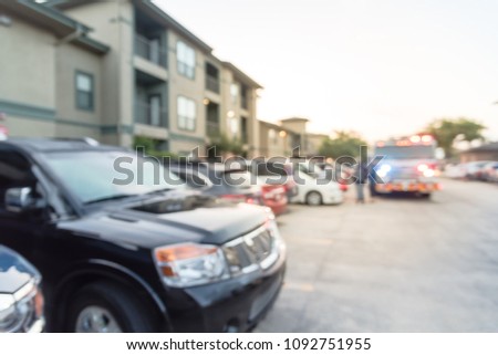 Blurred abstract fire trucks at apartment incident in Texas, USA. Multi-floor residential building complex. Motion background fire accident damage with bokeh lights, insurance concept