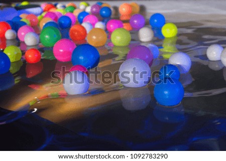 colorful balls on a water surface in swimming pool under the night lights