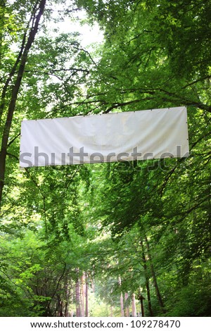 Blank white board banner and green trees