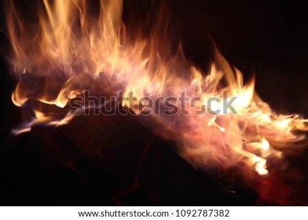 Close up view inside the bbq grill on burning open fire with red flame, hot  charcoal briquettes and embers. Abstract background, long exposure shot, concept of evil, anger and danger