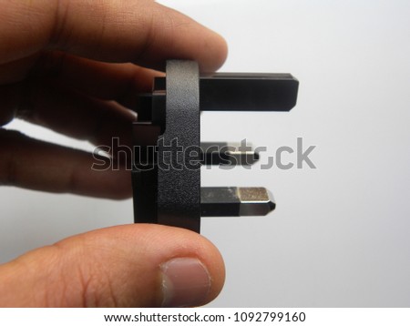 Hand of man holding black color 3 pin power plug adapter