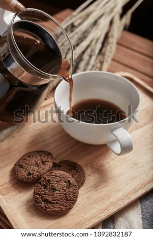 Black coffee on wooden tray and dried flowers with cookies