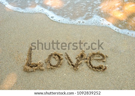 Write the word love on the beach. Soft focus wave.