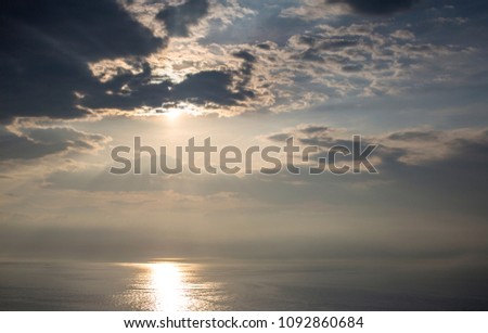 beautiful moody storym sky withclouds hiding the sun and reflection in the sea below