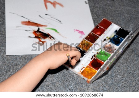 Picture of the child's hands drawing with watercolor paint. Watercolor abstraction.