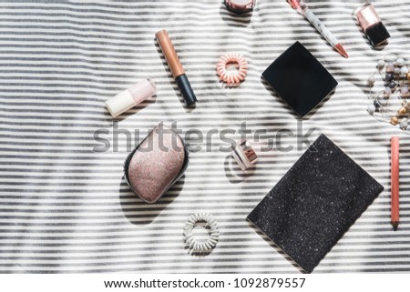 Woman's glamour beauty products flatlay on white and gray striped bedsheets. Fashion blogging concept