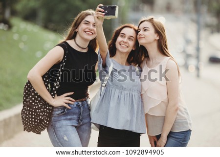 Friendship, togetherness, city walk, traveling, leisure, hobby. Three friends taking selfie outdoors. Woman using retro camera to take photos