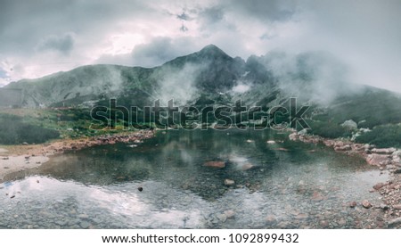 The fairy tale misty landscape the mountain Kalnate pleso lake surrounded by the mighty Tatras. Tatranska Lomnica, Slovakia. Ideal background in grey shades for the collages and illustrations.