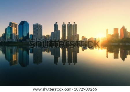 cityscapes silhouette building in modern skyline city at morning with sunrise and water reflection.