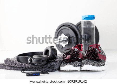 Sport concept - sneakers, dumbbells, towel, earphones on light background. Selective focus.