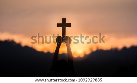hands off children holding christian cross with light sunset.