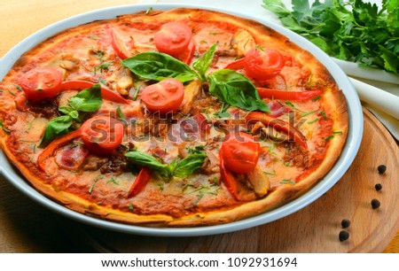 Pizza with tomatoes, mozzarella cheese, pepper and basil. Tasty Italian pizza on a wooden pizza board.