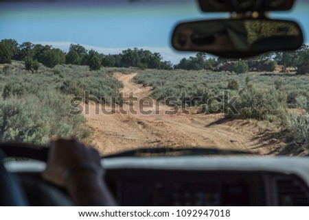 Dirt / sand road driving with offroad vehicle, picture taken from backseat with adventurous driver visible with hands on wheel and in rear view mirror