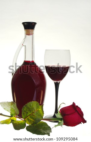 Glass of red wine,  bottle of wine and red rose. White background.
