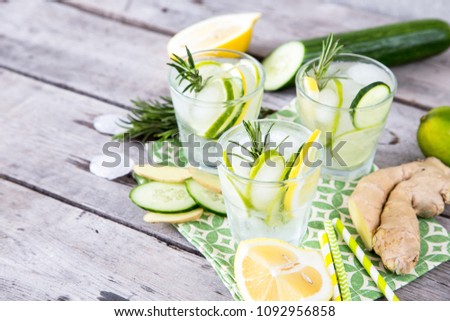 Homemade Lemonade with Lime, Rosemary, Ginger, Cucumber and Ice on a Wooden Background.