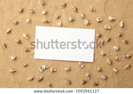 White empty frame on sand with sea shells as background. Blank card on beach sand with small shells texture.
