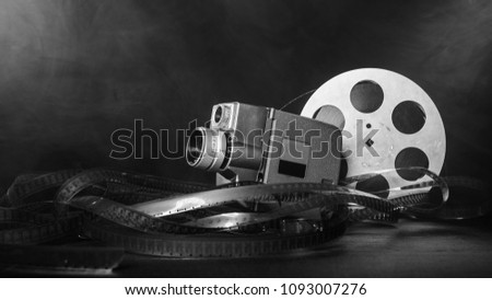 8 mm movie camera with a reel of film in smoke. dark background. black and white