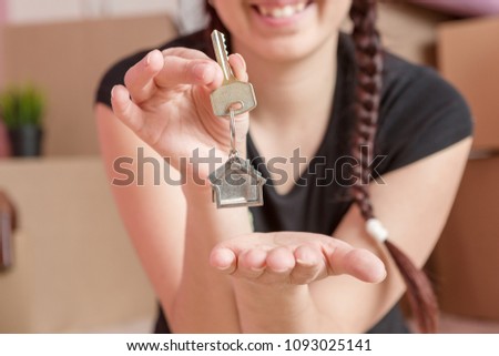 Image of young brunette with keys from apartment against blank wall