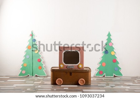 Christmas winter vacation. Firs of cardboard and box with a TV picture.