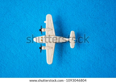 Top view on white plane with two propellers. Children scale models of airplane. Small aircraft bauble with engines on rounded wings. Plastic playthings isolated on blue background