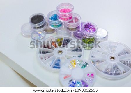 Set of bright glitters in transparent jars, top view on white table