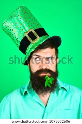 St. Patrick's Day. Bearded man in leprechaun hat. Portrait of pensive man. Clover in mouth. Bearded leprechaun. Happy Irish leprechaun with black beard. Bearded man.
