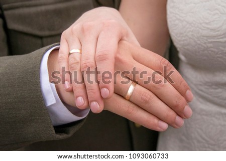 Focus on female and male hands with wedding rings. Arms of married couple. Man in official suit and woman in bright dress with pretty ornament